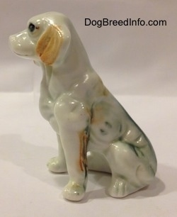 The left side of an English Setter bone china figurine that is in a sitting pose. The figurine has green along the back of its legs and down the back of its body.