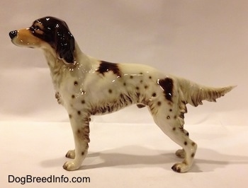The left side of a brown and white porcelain English Setter figurine. The figurine has brown spots all of its body.
