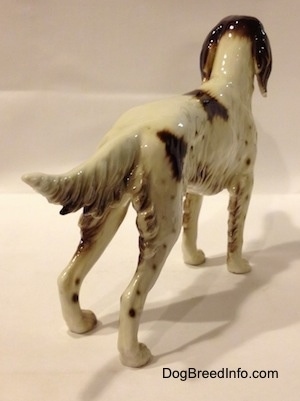 The back right side of a brown and white English Setter porcelain figurine. The figurine has a long body and a medium length tail.
