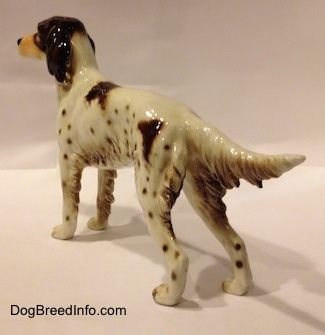 The back left side of a porcelain brown and white English Setter figurine. The tail of the figurine is extended out and it is level with its body.