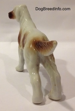 The back of a bone china brown and white English Setter in a standing pose figurine. It is hard to diffentiate the ears from the head of the figurine.