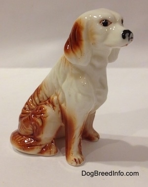 The right side of a bone china red and white English Setter figurine. The figurine has black circles for eyes.
