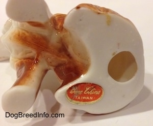 The underside of the bone china English Setter figurine. The figurine has a hole in the bottom and it has a sticker on it. The sticker reads - Bone China Taiwan.