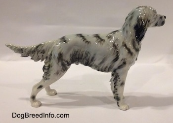 The right side of a white and black English Setter porcelain figurine. The figurine has long legs and small paws.
