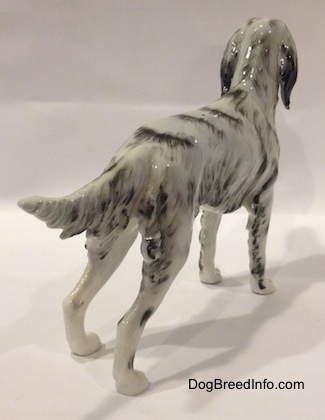 The back right side of a black and white porcelain English Setter figurine. The figurine has hair along the back of its legs.