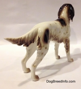 The back right side of a white with brown English Setter in a standing pose figurine. The figurine has brown ears.
