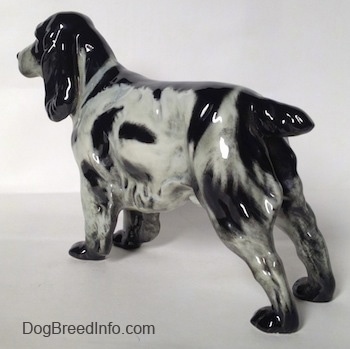 The back left side of a figurine of a black and white English Springer Spaniel. The figurine has hair around the trim of its body.