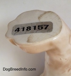 Close up - A sticker that is on the bottom of the left paw of a English Springer Spaniel figurine that reads - 418157.