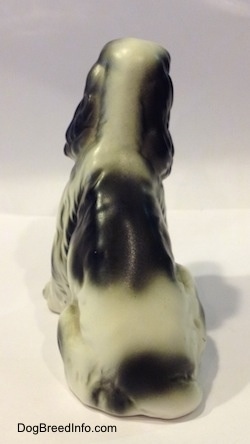 The back of a black and white English Springer Spaniel bone china figurine in a sitting pose figurine. It is hard to see the tail of the figurine.