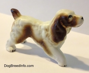 The right side of a brown and white English Springer Spaniel figurine. The figurine has black circles for eyes.