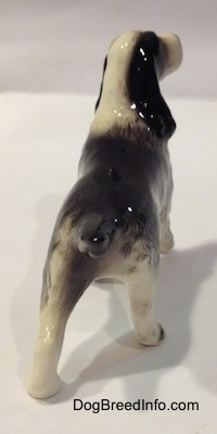 The back of a ceramic figurine of a black with white English Springer Spaniel. The figurine has a short black tail.