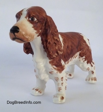 The front left side of a figurine of a English Springer Spaniel. The nose of the figurine is black.