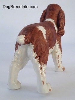 The back right side of a English Springer Spaniel figurine. The figurine has a short brown tail that is white at the tip.
