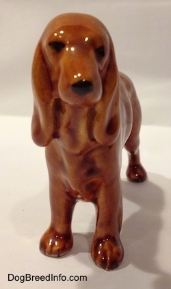 A brown Field Spaniel ceramic figurine. The figurine has black circles for eyes and a nose.