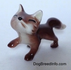 The front left side of a baby fox figurine. The figurine is looking up and it has black small paws.