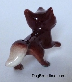 The back right side of a figurine that is of a Baby Fox. The tail of the figurine is white.