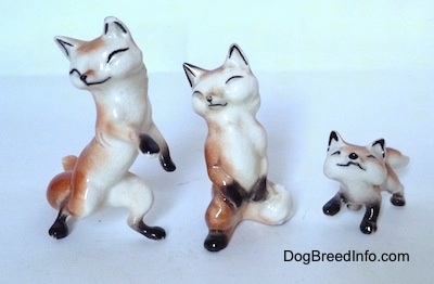 Three different fox figurines. Two of the foxes are on there hind legs and one is on a ll four and looking up.