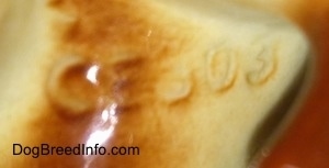 Close up - The underside of a fox figurine and engraved on it is the letter/numbers - CE303.