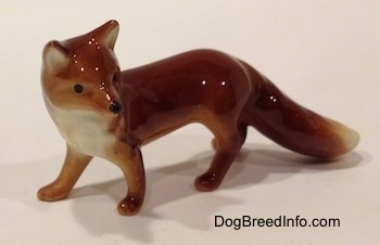 The front left side of a red fox figurine. The figurine has a white chest.