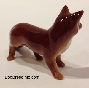 The front right side of a figurine of a red fox. The back of the figurine is glossy.