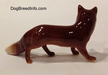 The right side of a red fox figurine. The figurine has a glossy finish.