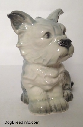 A white with black French Bull Tzu figurine is in a sitting pose. The figurine has fine chest details.