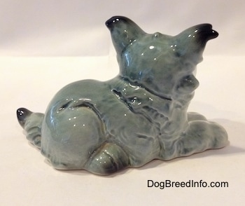 The right side of a figurine of a white with black French Bull Tzu in a laying down pose. The figurine has hair details on its side.