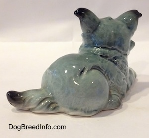 The back right side of a white with black French Bull Tzu figurine in a laying down pose. The figurine has a short hairy tail.