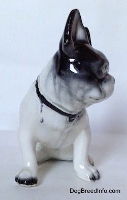 A white and black figurine of a French Bulldog in a sitting pose. The figurine has black tipped nails.