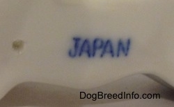 Close up - The underside of a porcelain French Bulldog figurine and it has the word - JAPAN - stamped on it.