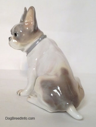 The back left side of a white with gray French Bulldog figurine. The figurine has a short tail.