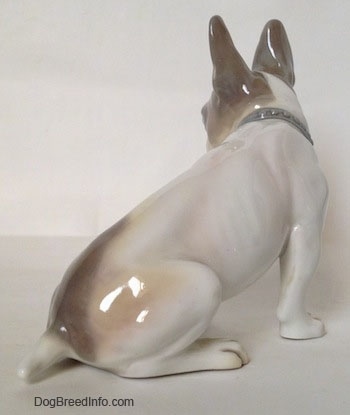 The back right side of a figurine of a white with gray French Bulldog figurine. The figurine has a detailed body, its rib bones are slightly visible.