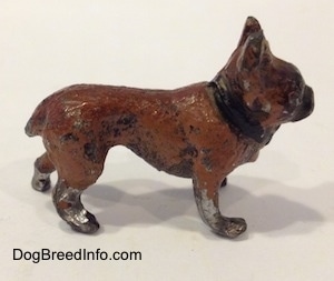 The right side of a brown with black metal French Bulldog figurine. The paint on the legs and body of this figurine are chipped.