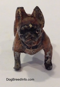 A metal figurine of a brown with black French Bullldog. The figurine has short brown legs and short black paws.