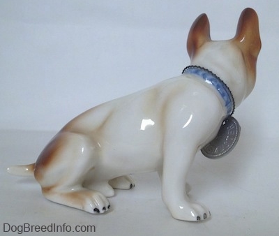 The right side of a figurine of a brown and white French Bulldog figurine. The figurine has 2 brown paws and 2 white paws, but they all have black nails.