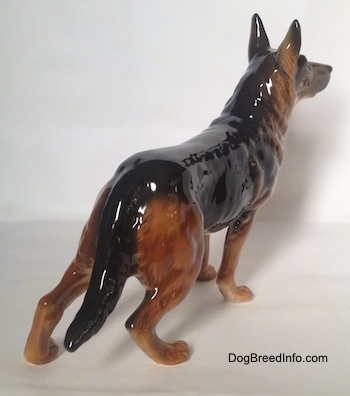 The back right side of a figurine of a brown with black German Shepherd.The figurine has muscle details on its legs and along its body.