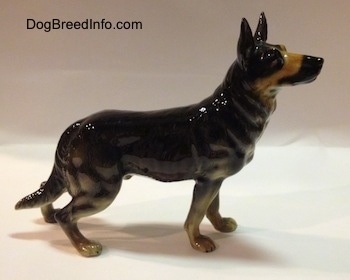 The right side of a figurine of a black with tan German Shepherd standing. The figurine has muscle details in legs.