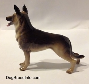 The left side of a black with tan German Shepherd standing figurine. The figurine has its ears standing in the air.