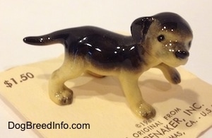 The right side of a black with tan German Shepherd standing puppy figurine. The figurine has black tipped paws.