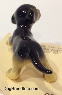 The back of a black with tan German Shepherd puppy figurine. The tail of the figurine is sticking out.