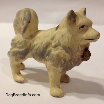 The right side of a German Spitz ceramic dog figurine. The figurine is white with gray brushings.