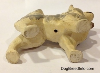 The underside of a ceramic German Spitz figurine that has a small hole on it.