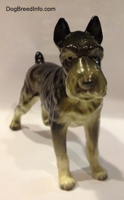 A black, grey and white figurine of a bone china Giant Schnauzer. The figurine has black circles for eyes.