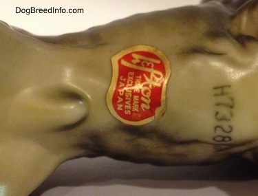 The underside of a bone china Giant Schnauzer figurine. There is a Lefton sticker on the underside of the figurine. Above the sticker is the nu,ner 'H7328'.