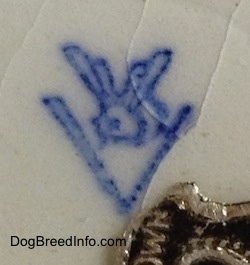 A close up of a blue stamp of the letter V with a bee on the top of the letter