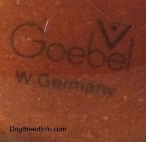 Close up - The underside of a brown figurine that is scratched and the stamp of Goebel W.Germany is on it.