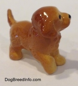 The front right side of a figurine of a Goden Retriever puppy. The figurine has a slightly lifted right paw.