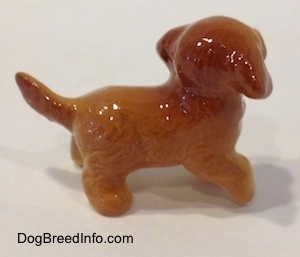 The right side of a Golden Retriever puppy figurine. The figurines tail is sticking out and up.