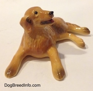 A figurine of a Golden retriever in a laying down pose. The figurine has brown tipped paws.