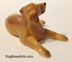 The front right side of a Golden Retriever figurine in a laying down pose. The figurine has long drapped ears.